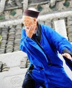 photo of a Chinese man in a bright blue robe practicing Qigong