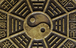Bronze-colored plate with Yin Yang symbol in the middle surrounded by Chinese lettering