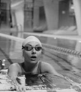 a swimmer with goggles on rests at a pool's edge while taking a breath